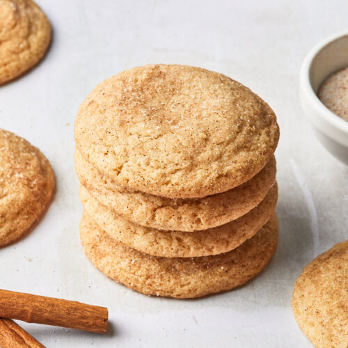 A stack of dairy free snickerdoodle cookies, next to a few cinnamon sticks.